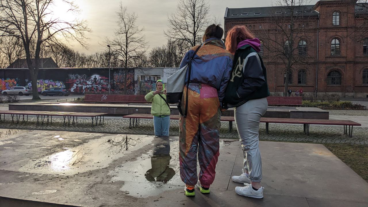 zwei Menschen sitzen in der Mitte eines trockengelegten Springbrunnens, Kopf an Kopf gelehnt