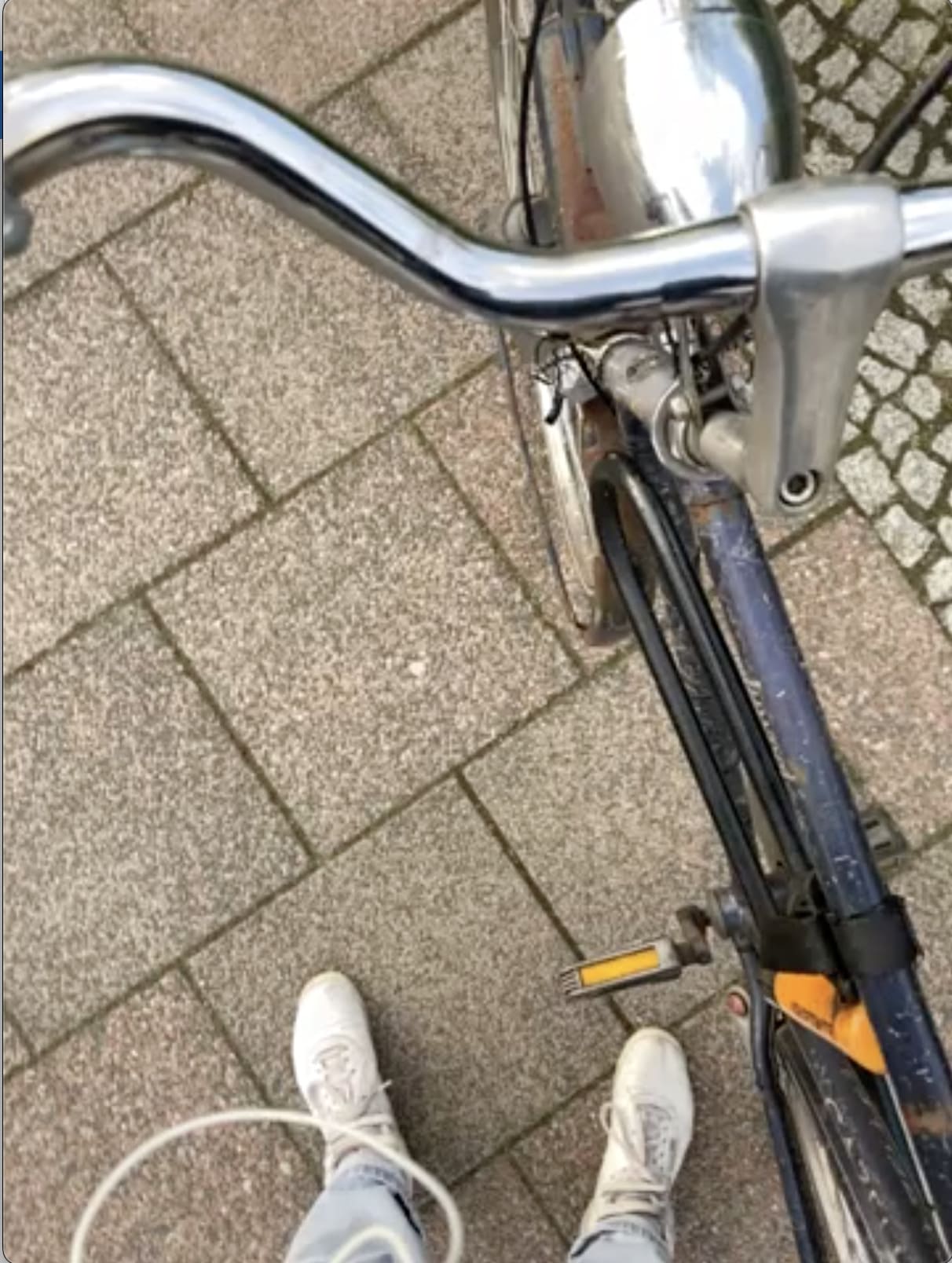Lenker eines Hollandrades und weiße Tunrschuhe aus der Vogelperspektive